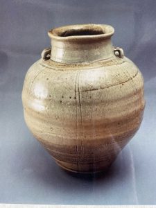 A large brown vase with carvings made by David Collins