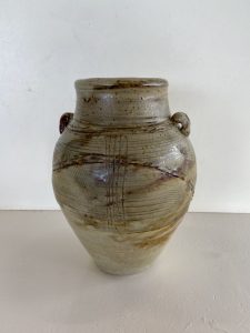 A large brown vase with carvings made by David Collins