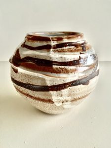 A small brown vase with carvings made by David Collins