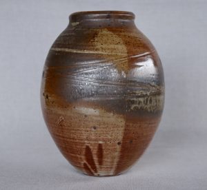 A large brown vase with carvings made by David Collins