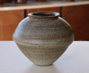 A brown vase with carvings made by David Collins