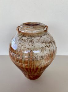 A large brown vase with carvings made by David Collins