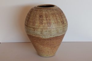 A large brown vase with carvings made by David Collins