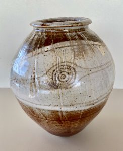 A white and brown vase with carvings made by David Collins